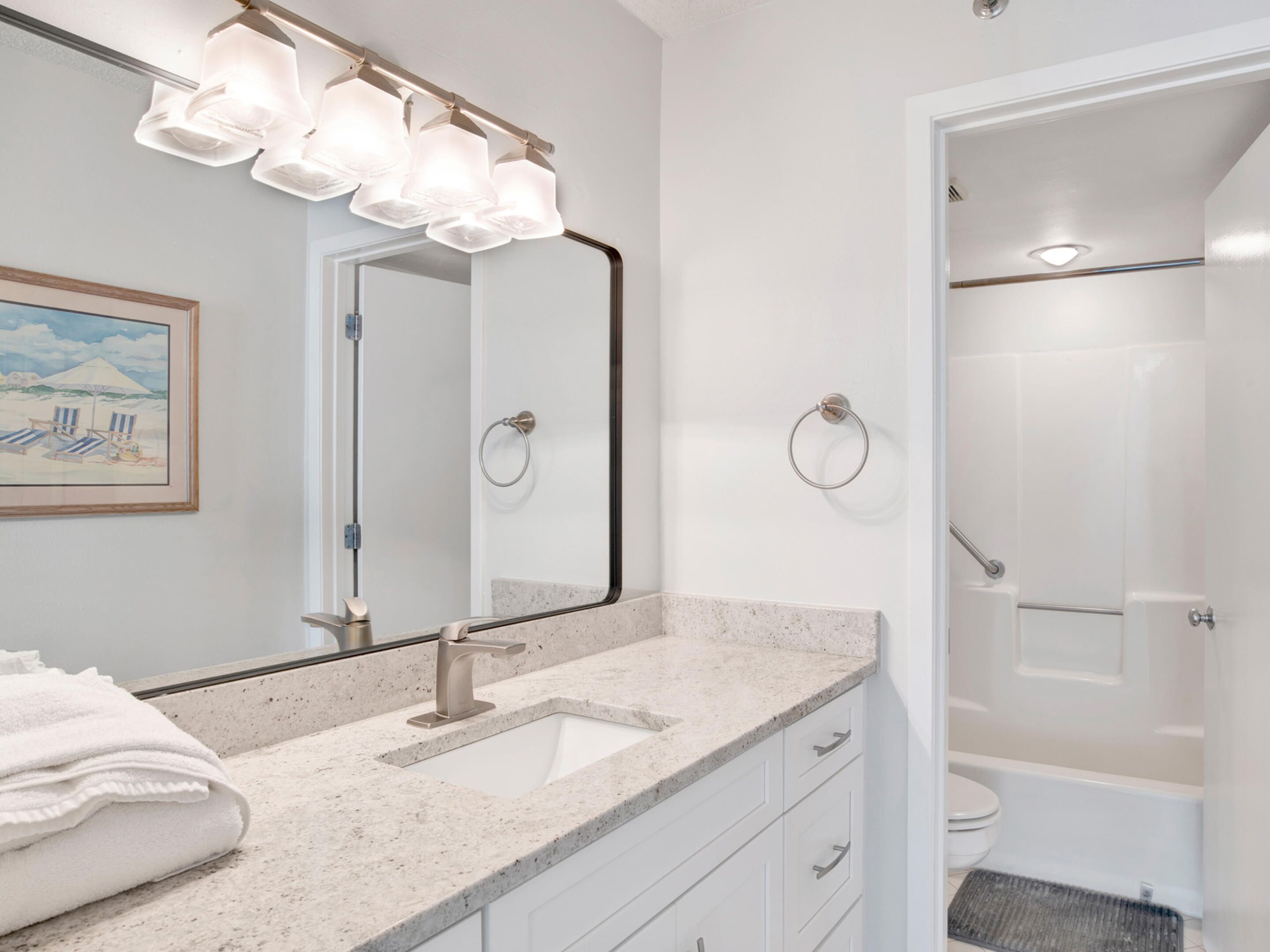 A bathroom with a large mirror, a sink with a modern faucet, and a shower area.