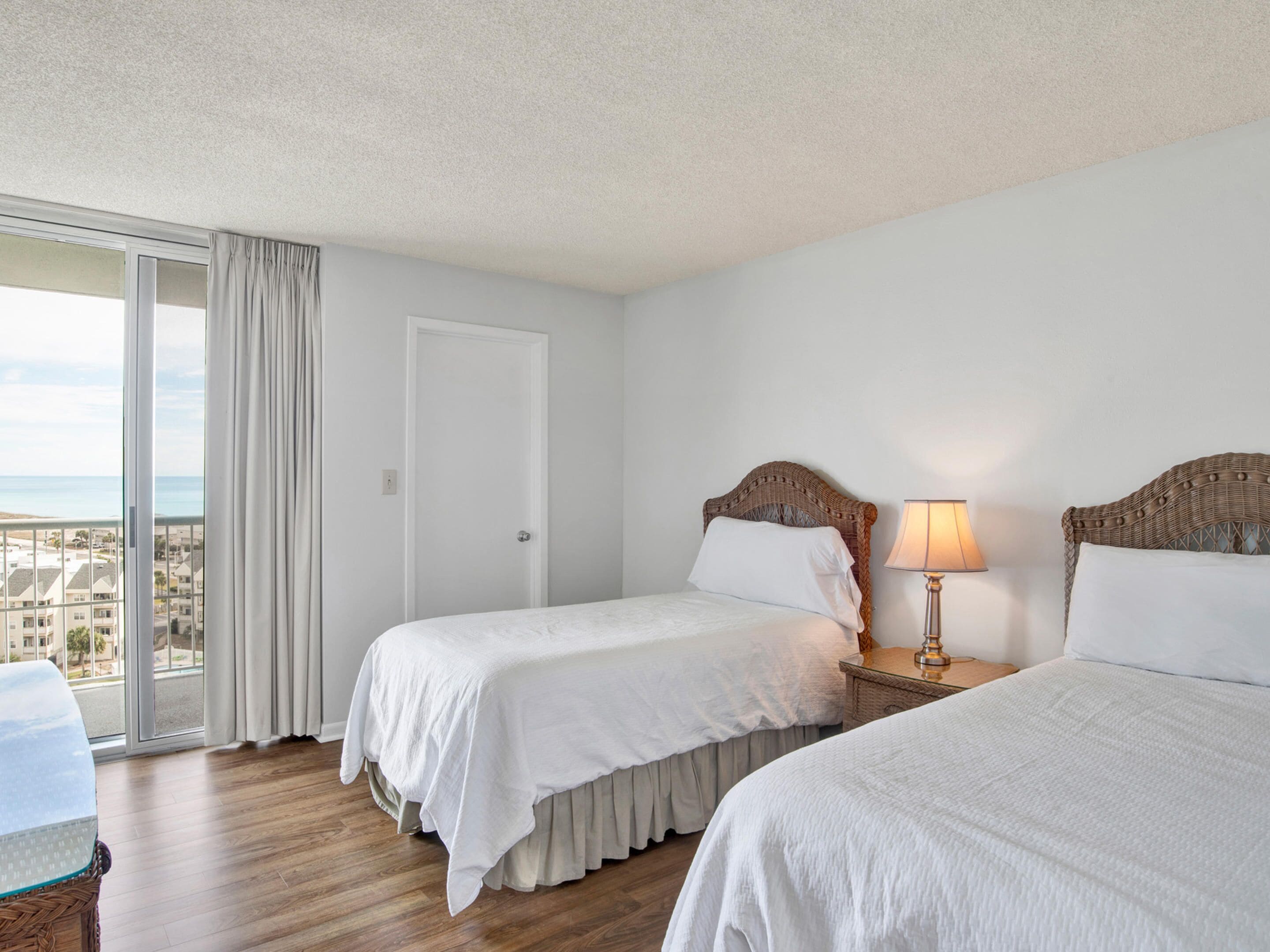 A hotel room with two beds, a balcony, and a view of the city.