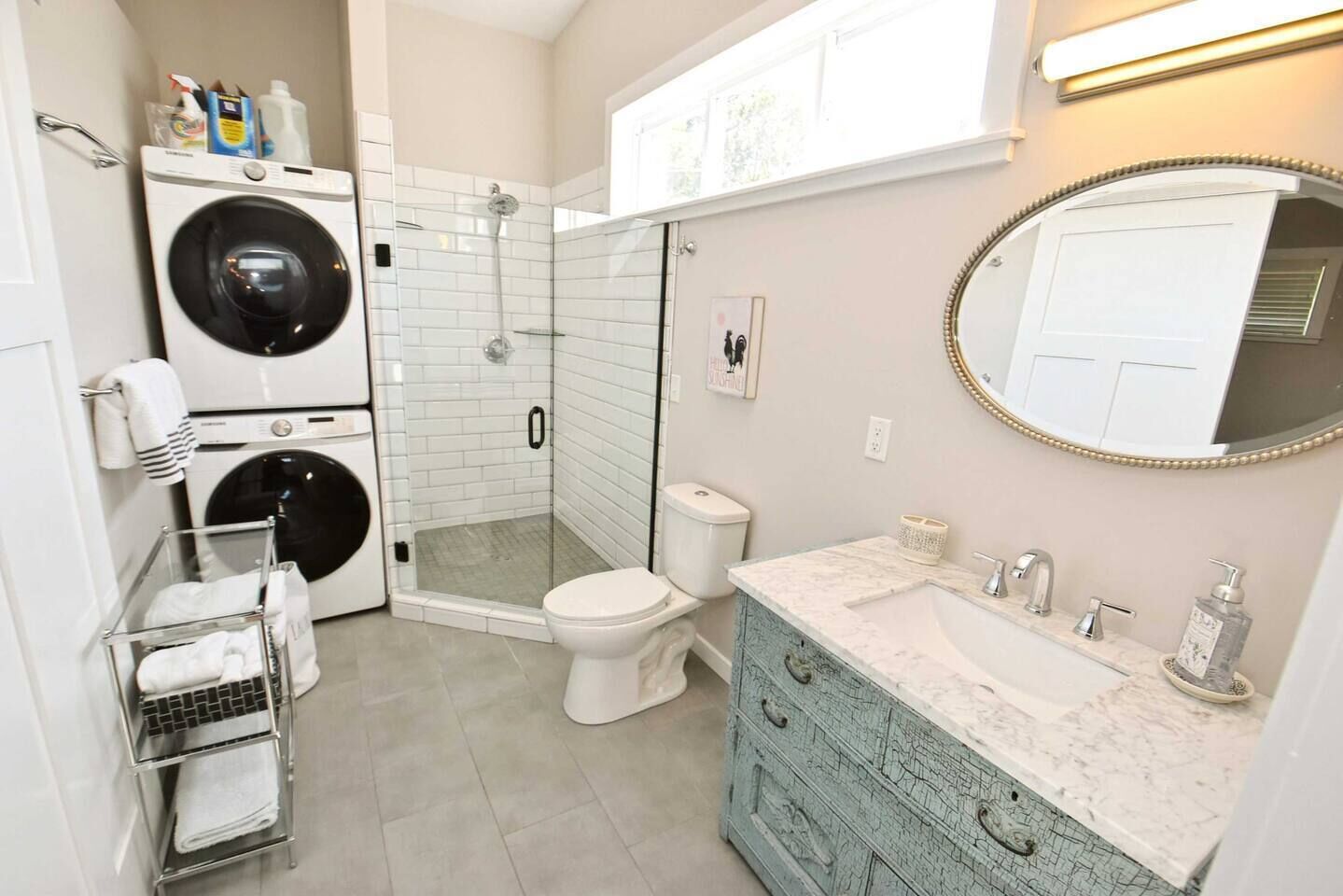A bathroom with a walk-in shower, a toilet, a washing machine, and a vanity with a mirror.