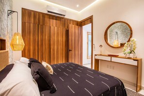 A modern bedroom with a bed, bedside table, and a mirror.