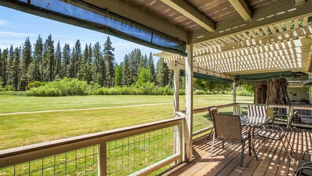 A covered outdoor area with a view of a golf course, wooden deck, and outdoor seating. - Views of the 8th Fairway at Plumas Pines-8 Aspen (Blairsden)