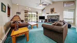 Una sala de estar con chimenea, ventilador de techo y televisor.
