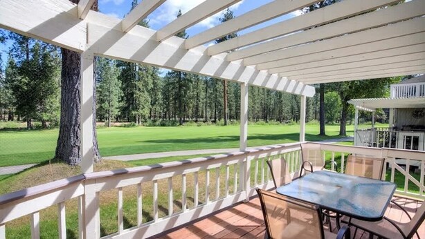 Un espacio exterior techado con una mesa y sillas, con vistas a un paisaje verde con árboles.
