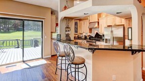 A modern kitchen with a large island, wooden cabinets, and a view of a deck.