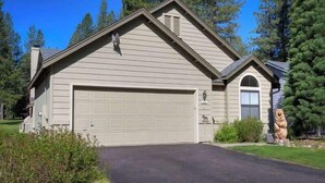A single-story house with a garage, a small porch, and a statue of a bear.