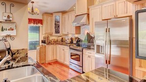 A modern kitchen with wooden cabinets, stainless steel appliances, and a marble countertop.