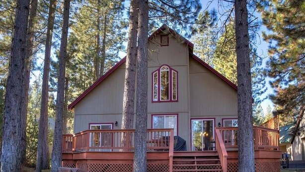 A cabin with a wooden deck and a covered porch, surrounded by tall pine trees. - Mountain Oaks - 35 Oak Court PET! (Blairsden)