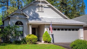 Une maison de plain-pied avec un garage, un porche à l’avant et un petit jardin devant.