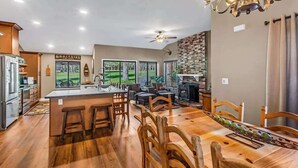 A spacious kitchen with a central island, bar stools, and a dining area with wooden chairs. - Stunning on the 17th Fairway - 119 Cottonwood Dr (Blairsden)