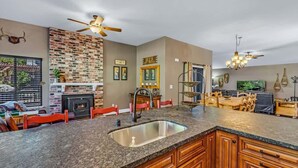 A kitchen with granite countertops, wooden cabinets, a built-in sink, and a brick accent wall. - Stunning on the 17th Fairway - 119 Cottonwood Dr (Blairsden)