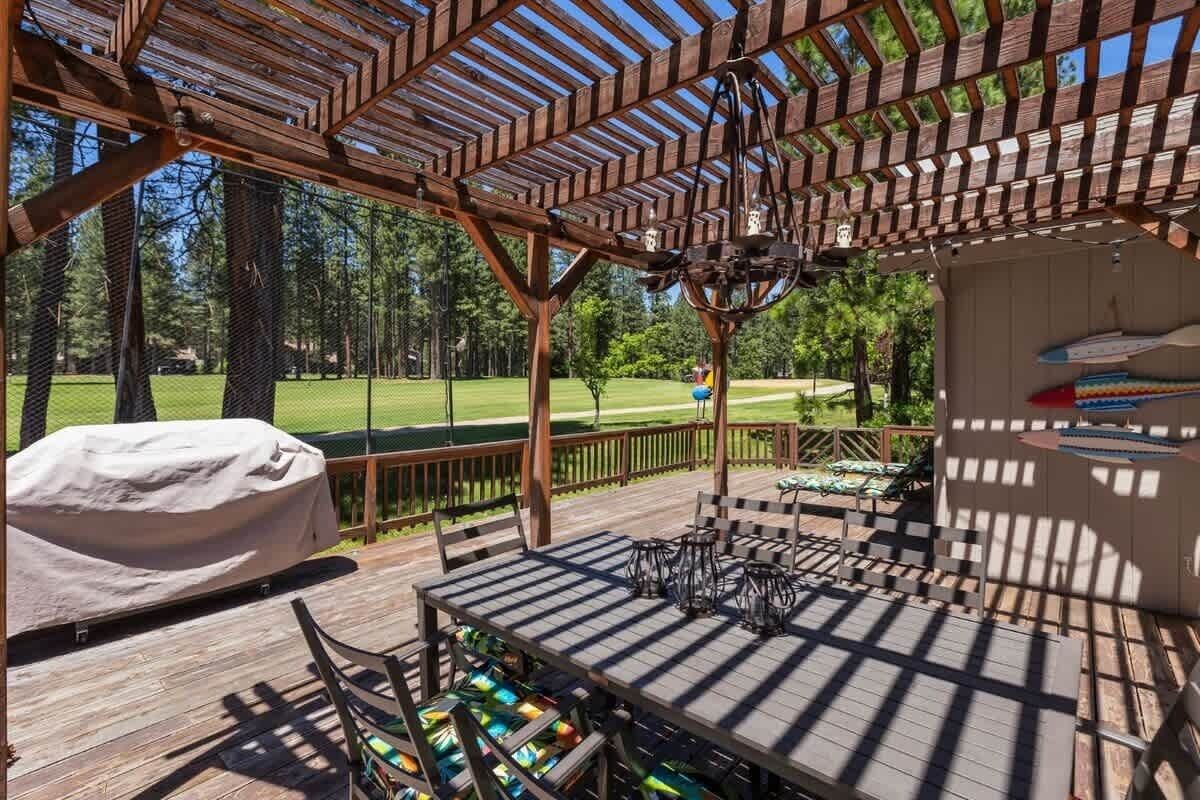 A wooden deck with a covered barbecue area, outdoor seating, and a view of a golf course.