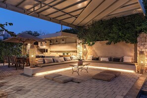 An outdoor patio with a built-in seating area, a table, and a pergola providing shade.