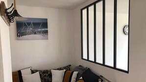 Un dormitorio con una cama, almohadas, un reloj de pared, un cuadro y una ventana con persianas.
