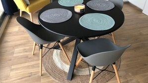 Un comedor con una mesa negra, cuatro sillas y una vela.