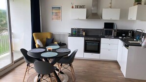Una cocina moderna con comedor, que incluye una mesa redonda con sillas, horno empotrado y vistas amplias a través de un ventanal.