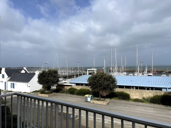 A marina with multiple sailboats docked, a building with a blue roof, and a white building with a blue door.