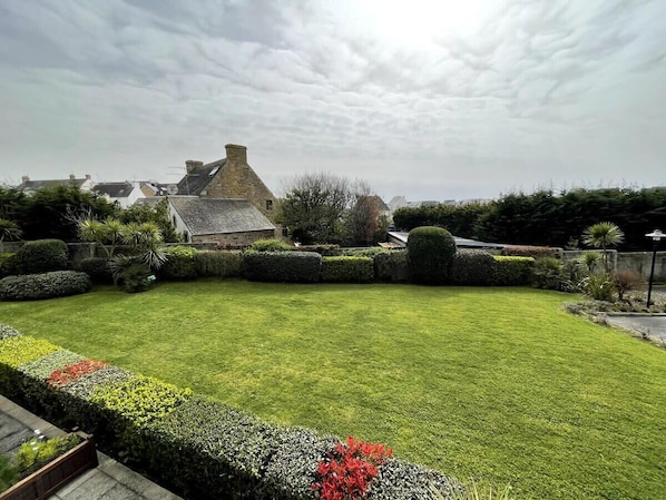 A well-maintained garden with a lawn, hedges, and flowering plants.
