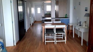 A modern kitchen with a dining area, wooden flooring, and a pendant light. - Turpault vue mer port maria quiberon 2* (Quiberon)