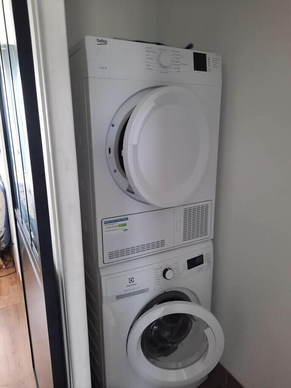 A front-loading washing machine and dryer stacked vertically in a laundry room.