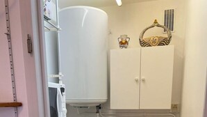 Eine kleine Küche mit einem weißen Kühlschrank, einer Mikrowelle, einem Spülbecken und einer kleinen Mülltonne.