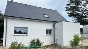 A modern house with a sloped roof, white exterior walls, and two windows. - Maison Tamaris. avec jardin et clos (Quiberon)