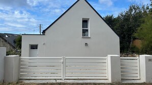 A white building with a triangular roof, a small window, and a gate. - Maison Tamaris. avec jardin et clos (Quiberon)