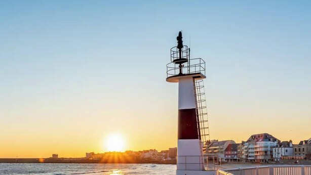 A lighthouse with a white and red top, located on a beach with a stone wall and white railing. - Maison Tamaris. avec jardin et clos (Quiberon)