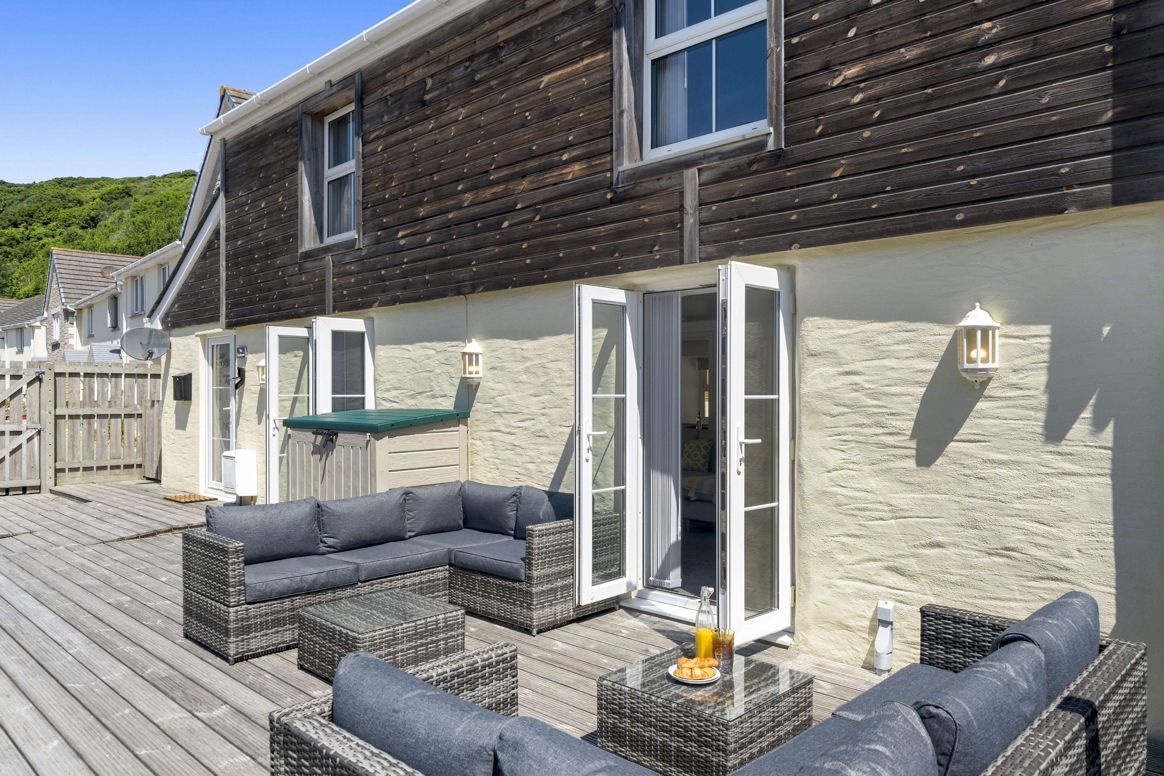A wooden deck with outdoor furniture, including sofas and tables.
