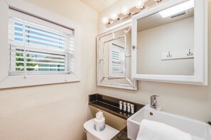 Une salle de bain avec un grand miroir, un meuble-lavabo et une baignoire.