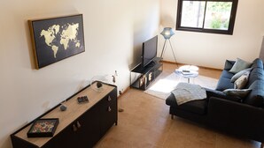 Un salon avec un canapé, un téléviseur, un meuble en bois et une carte du monde accrochée au mur.