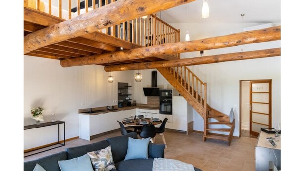 Un vaste espace de vie comprenant un escalier en bois, une cuisine et un coin repas.
