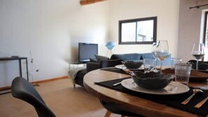 Un coin repas avec une table ronde, des chaises noires et un téléviseur en arrière-plan.