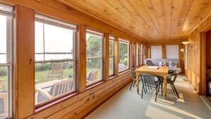 Una baita di legno con ampie finestre, un'area pranzo con tavolo e sedie, e vista sull'esterno.