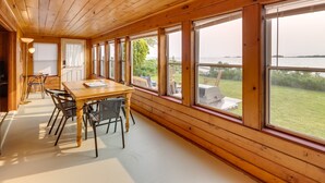 Una stanza con rivestimento in legno, un tavolo grande e sedie, ampie finestre e vista sull'esterno.