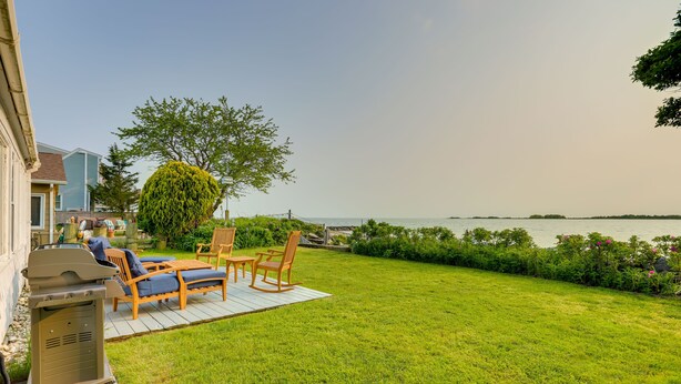 Ein Garten mit Grill, Gartenmöbeln und Blick auf das Wasser.