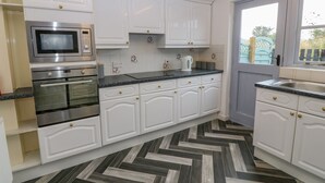 Une cuisine moderne avec des armoires blanches, des appareils en acier inoxydable et un sol à motifs en chevrons.