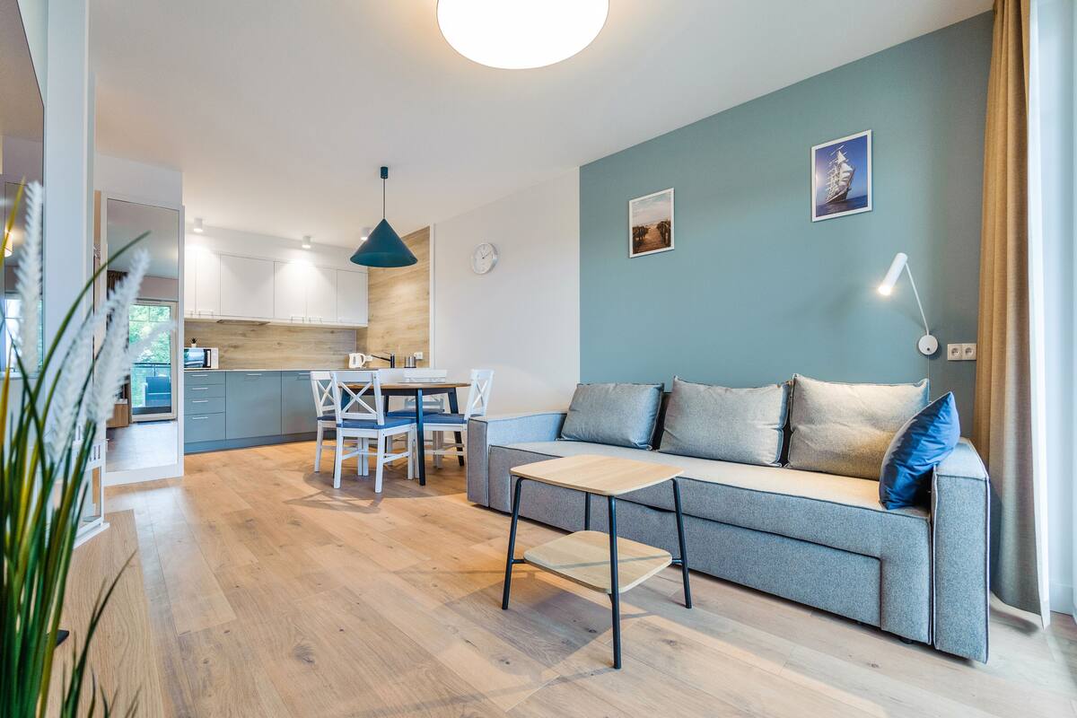 A modern living room with a sofa, coffee table, and dining area.