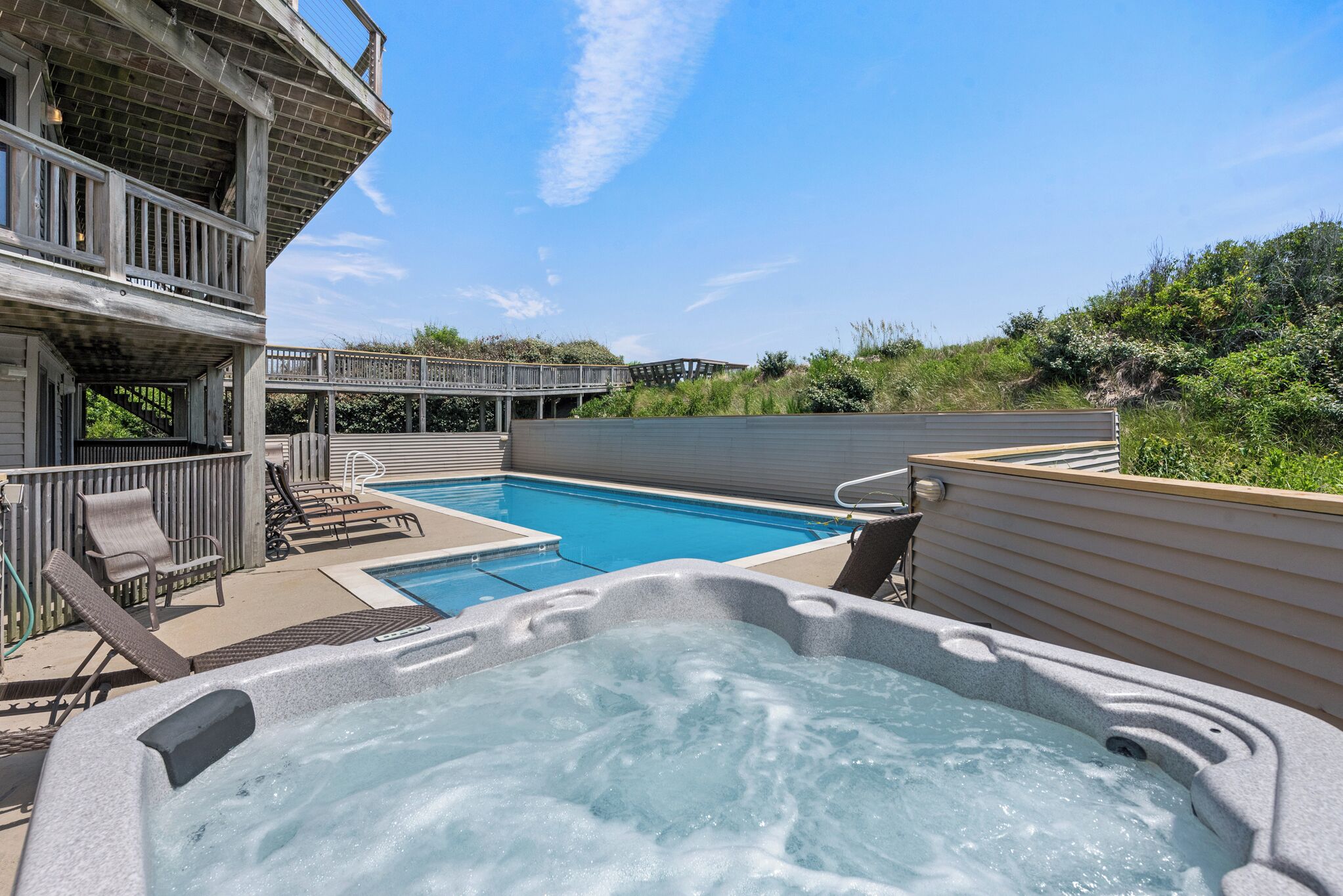 Una piscina con idromassaggio, lettini e un solarium in legno.