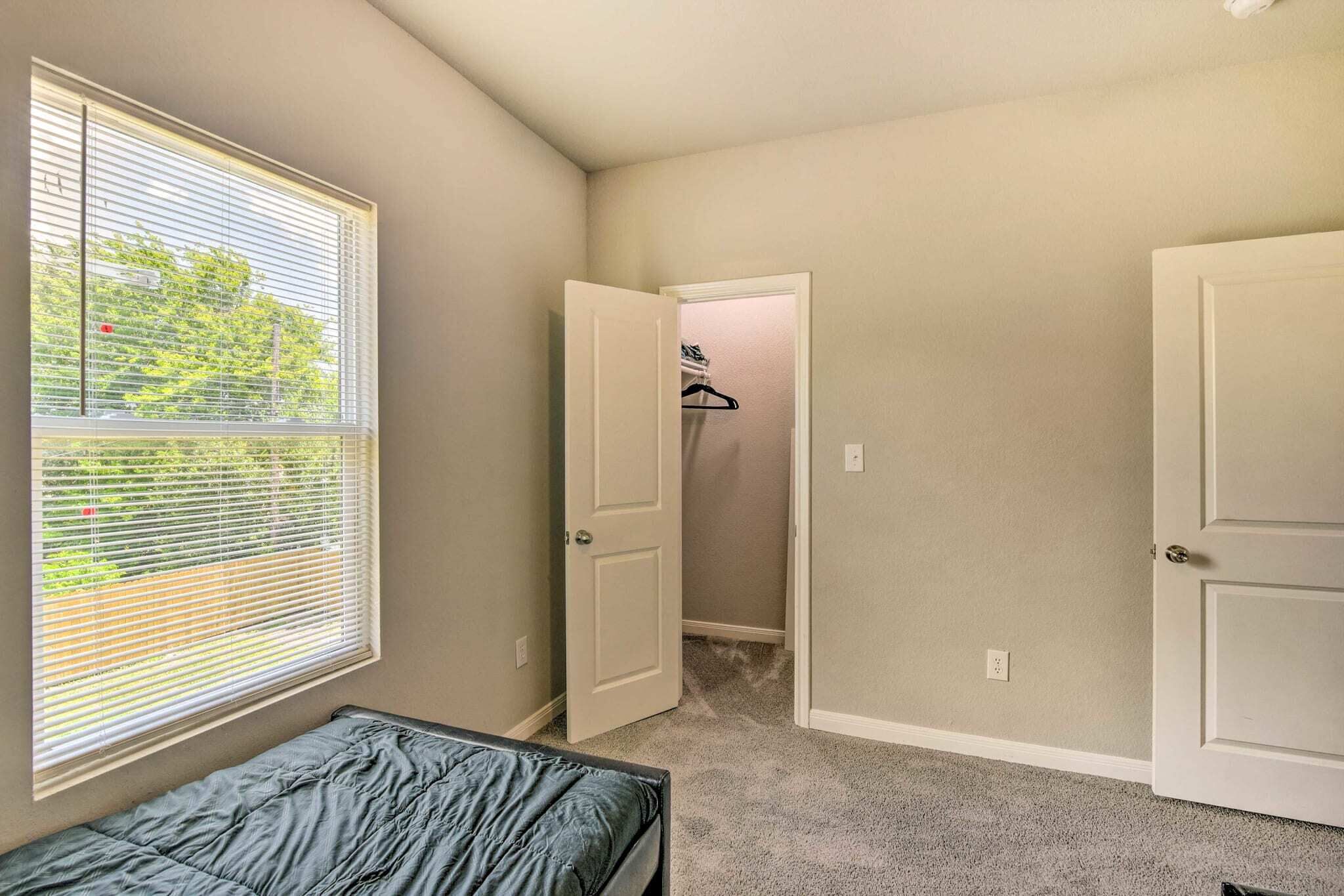 Un dormitorio con una cama individual, una ventana con persianas y un armario con perchero.