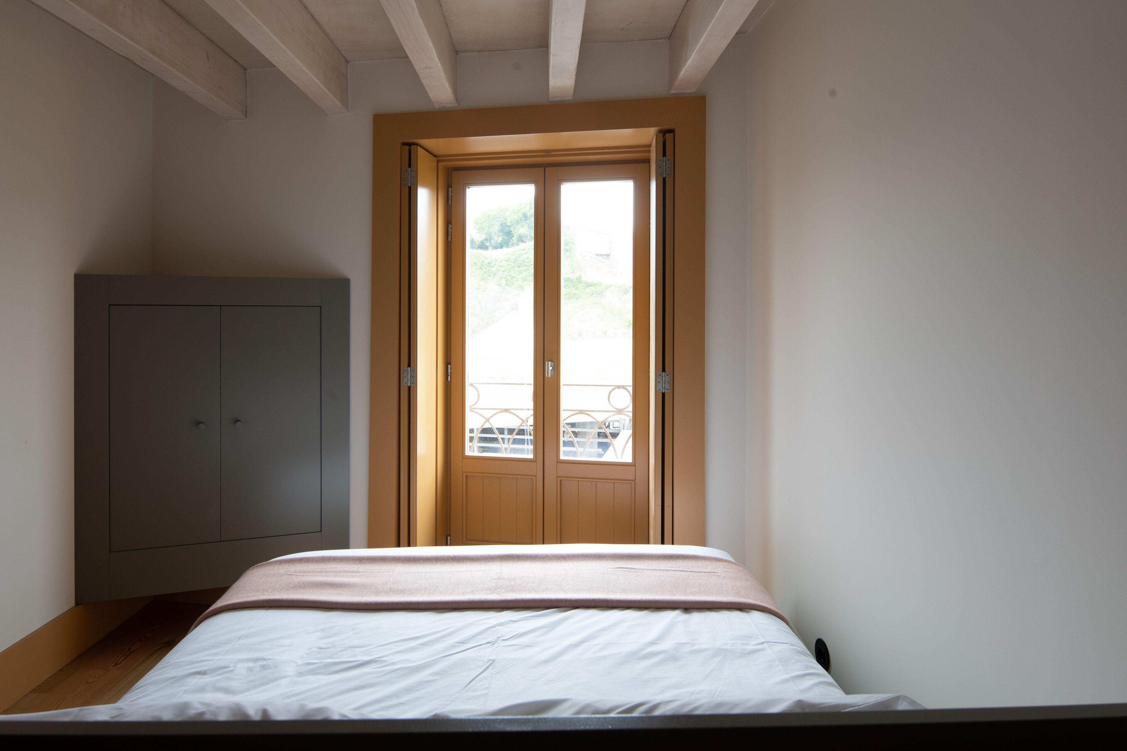 Une chambre à coucher avec un lit, une armoire et une fenêtre donnant sur un paysage verdoyant.