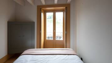 Une chambre à coucher avec un lit, une armoire et une fenêtre donnant sur un paysage verdoyant.