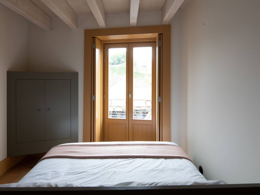 Une chambre à coucher avec un lit, une armoire et une fenêtre donnant sur un paysage verdoyant.