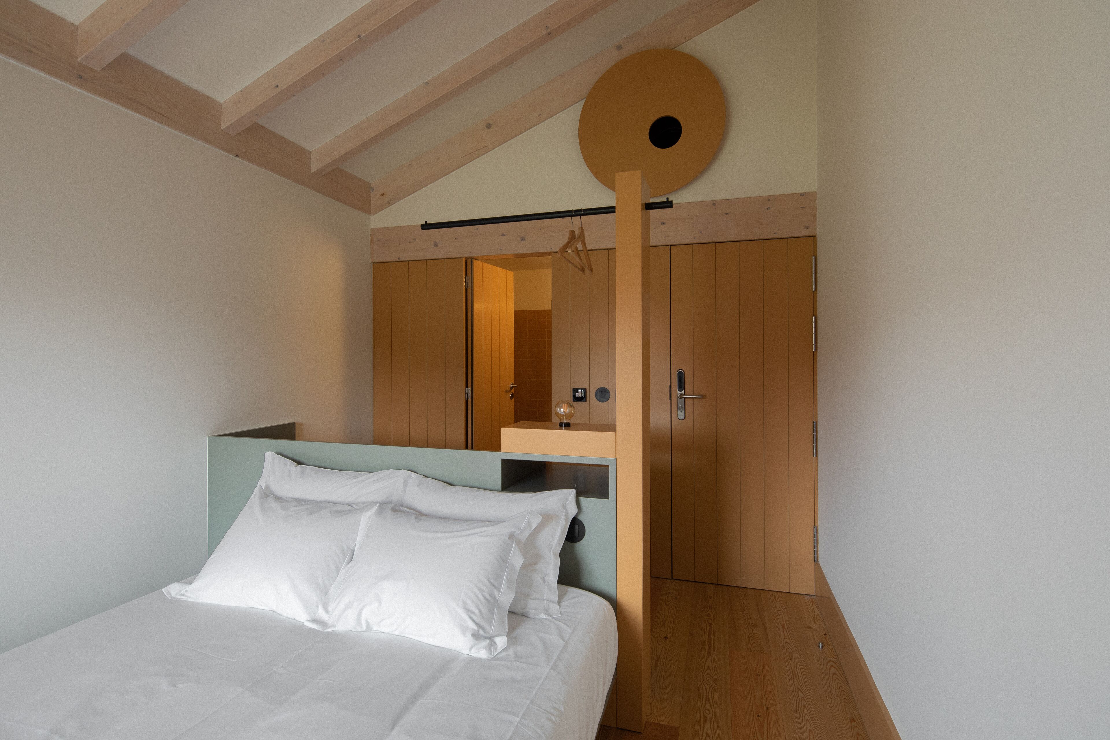 Une chambre à coucher avec un lit, une armoire en bois et un luminaire circulaire au plafond.