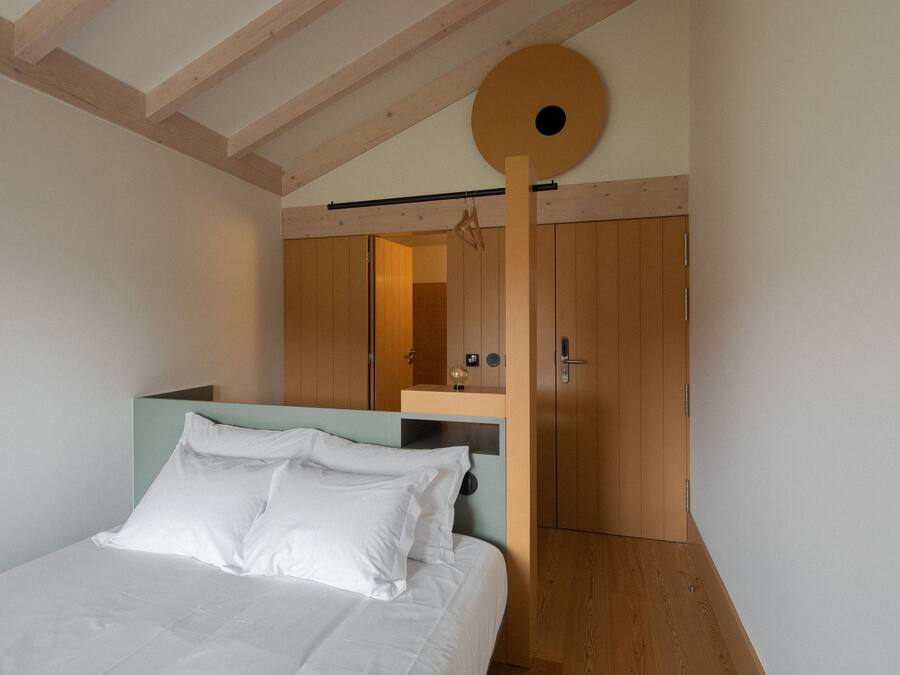 Une chambre à coucher avec un lit, une armoire en bois et un luminaire circulaire au plafond.