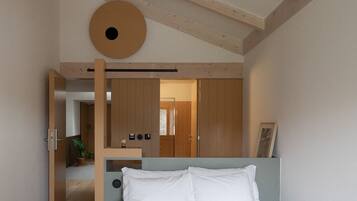 Una camera da letto con un letto, un soffitto in legno, un decoro murale circolare e una porta che dà su un'altra stanza.