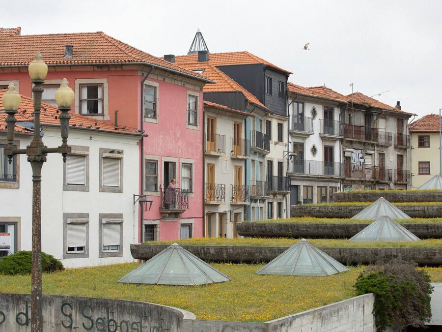 A row of colorful buildings with terracotta roofs and a street lamp in the foreground.