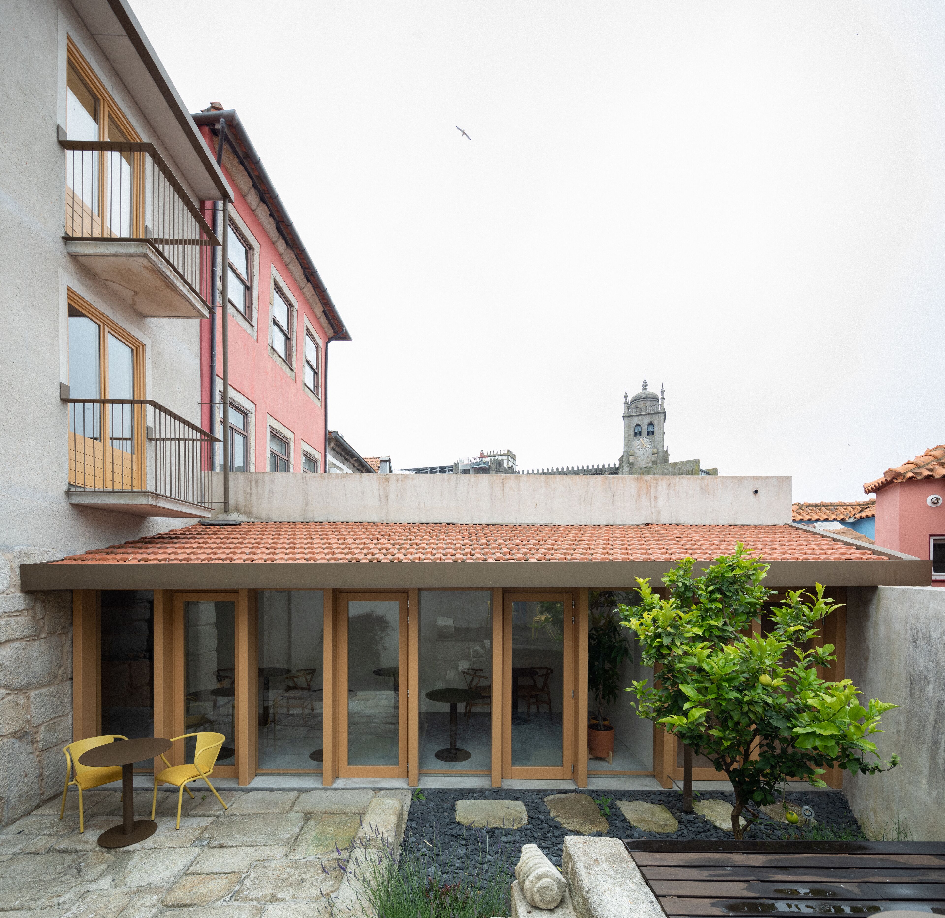 Un edificio con tetto in tegole rosse, ampie finestre e un balcone.