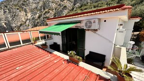 A rooftop terrace with red roofing, potted plants, and a green awning. - Sorrento Sunset Home (Meta)