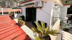 A building with a red roof, green shutters, and potted plants. - Sorrento Sunset Home (Meta)