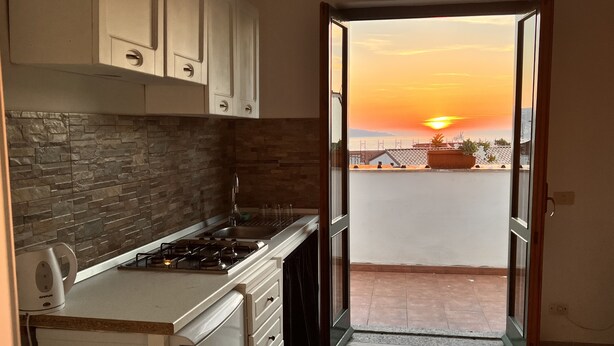 A kitchen with a gas stove, white cabinets, and a stone backsplash. - Sorrento Sunset Home (Meta)